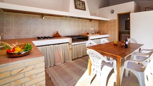 A kitchen with a wooden table and white chairs, a stove, and a tiled backsplash. - Vacation home Vicent by Interhome (Benissa)