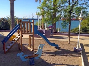 Une aire de jeux avec un toboggan, une structure d’escalade et une balançoire.