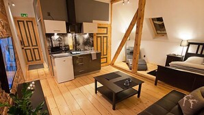 A compact living space with a kitchenette, a sofa, a coffee table, and a dining table.