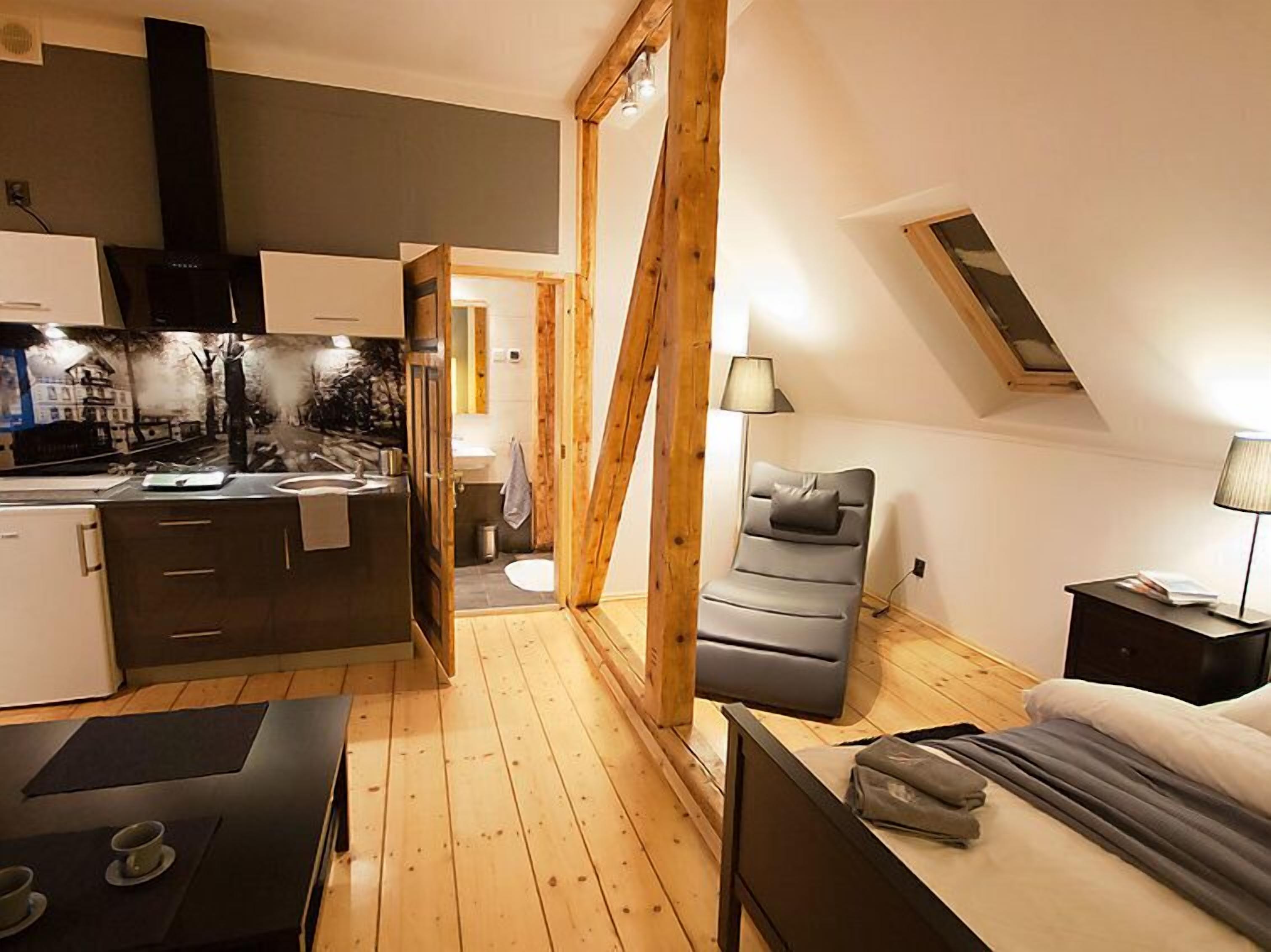 A compact, modern apartment with a kitchenette, a small bathroom, a sofa, and a bed.