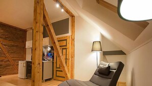A cozy room with a curved sofa, a lamp, and a kitchenette in the background.