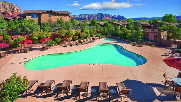 Ein Resort mit Pool, Liegestühlen und Bergblick.