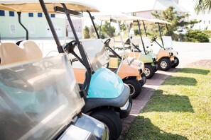 A row of golf carts parked on a paved path with grass on the sides. - Pet Friendly,Oceanfront duplex,direct access,community pool.Spinnaker's Reach (Emerald Isle)