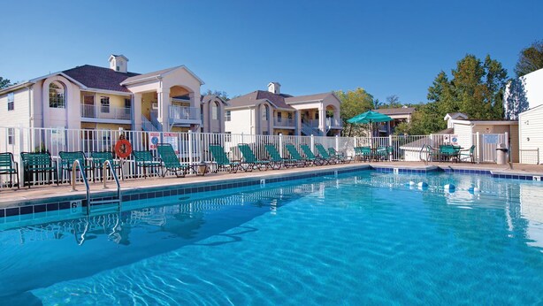 A swimming pool with lounge chairs and umbrellas, surrounded by multi-story buildings with balconies. - Spacious Branson  lodging with Beautiful scenery (Branson)
