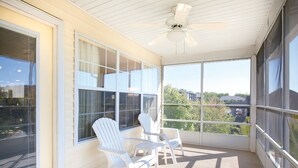 A covered balcony with large windows, white Adirondack chairs, and a ceiling fan. - Spacious Branson  lodging with Beautiful scenery (Branson)