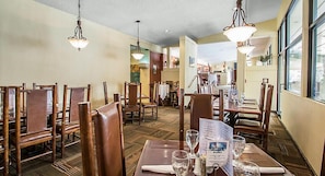 Un'area pranzo con tavoli e sedie in legno, un menu sul tavolo e lampade a sospensione.