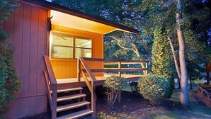 Una cabaña de madera con balcón, rodeada de árboles.
