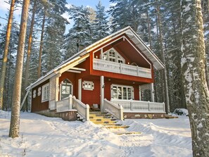 A two-story wooden cabin with a balcony, surrounded by snow-covered trees. - Honkaniemi by Interhome (Joensuu)