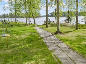 A concrete pathway leading to a lake with a hammock and a disc golf basket. - Honkaniemi by Interhome (Joensuu)