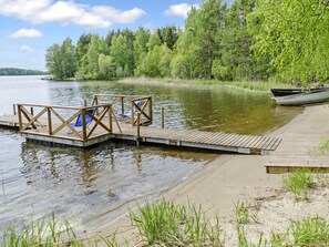A wooden dock extending into a calm lake, surrounded by dense green trees.