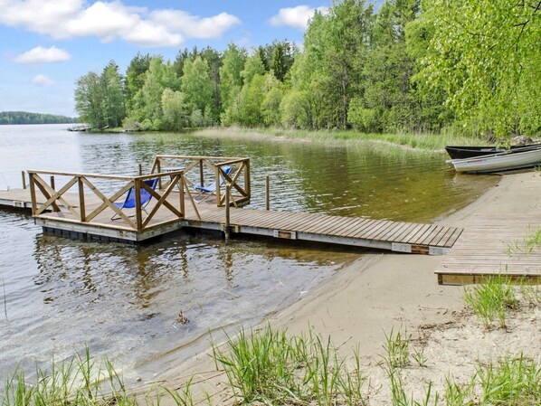 A wooden dock extending into a calm lake, surrounded by dense green trees.