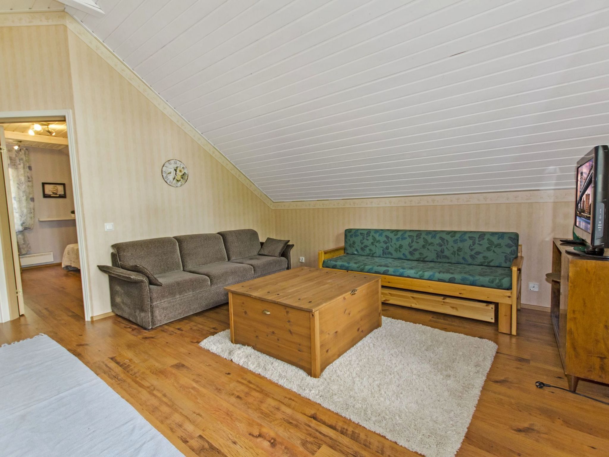 Una sala de estar estilo loft con techo de madera, un sofá, un sillón y una mesa de centro.