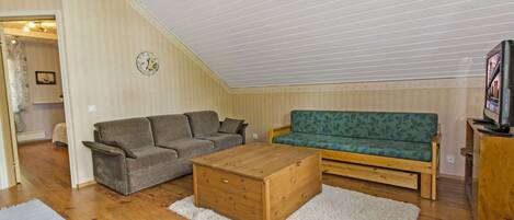 Una sala de estar estilo loft con techo de madera, un sofá, un sillón y una mesa de centro.