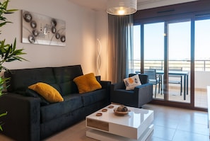 A modern living room with a sofa, a coffee table, and a balcony with a view.