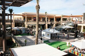 A shopping mall with multiple levels, outdoor seating areas, and a central atrium with a tent.