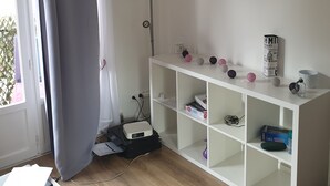 Une pièce comprenant un bureau blanc, une imprimante, une lampe et une étagère ornée d’objets décoratifs.