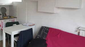Un espace de vie compact comprenant un coin cuisine, une table à manger et un canapé.