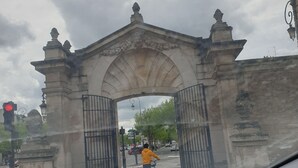 Une arche en pierre ornée de sculptures complexes, et un cycliste qui la traverse.