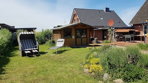 A wooden house with a tiled roof, a barbecue area, and two outdoor seating areas. - Sun-drenched first floor apartment on the dyke (Puttgarden)