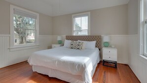 A bedroom with a large bed, two nightstands, a window, and a radiator.