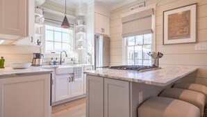 A modern kitchen with white cabinetry, a marble countertop, and a built-in stove. - Broad Creek Cottage in River Dunes (Oriental)