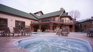 Un espace bien-être comprenant un jacuzzi, des chaises longues et un bâtiment doté d’un balcon.