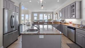 A modern kitchen with stainless steel appliances, granite countertops, and a large island with a sink. - Oceanfront with heated private pool (optional),beach access,close to town center (Emerald Isle)