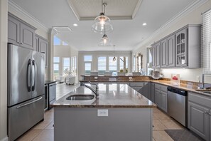 A modern kitchen with stainless steel appliances, granite countertops, and a large island with a sink.
