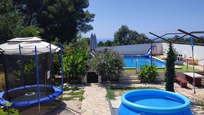 A backyard with a trampoline, a small pool, and a covered area.