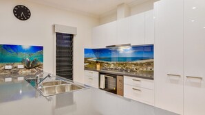 Eine moderne Küche mit Spüle aus Edelstahl, weißen Schränken und einer Uhr an der Wand.