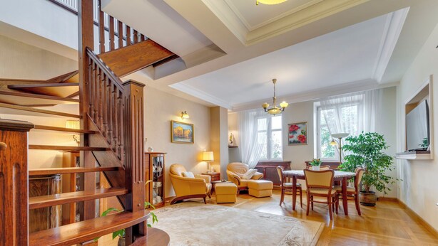 Un salon spacieux avec un escalier en bois, un coin repas et une grande fenêtre offrant une belle vue.