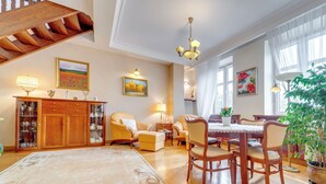 Un salon spacieux avec un escalier en bois, un coin repas avec des meubles en bois et une grande fenêtre agrémentée de rideaux.