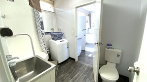 Ein kleines Badezimmer mit Waschbecken, Waschmaschine und Toilette.