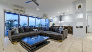 Een moderne woonkamer met een modulaire bank, een salontafel en grote ramen met uitzicht op de stad.