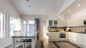 Une cuisine moderne avec des meubles blancs, un four encastré et un coin repas comprenant une table et des chaises.
