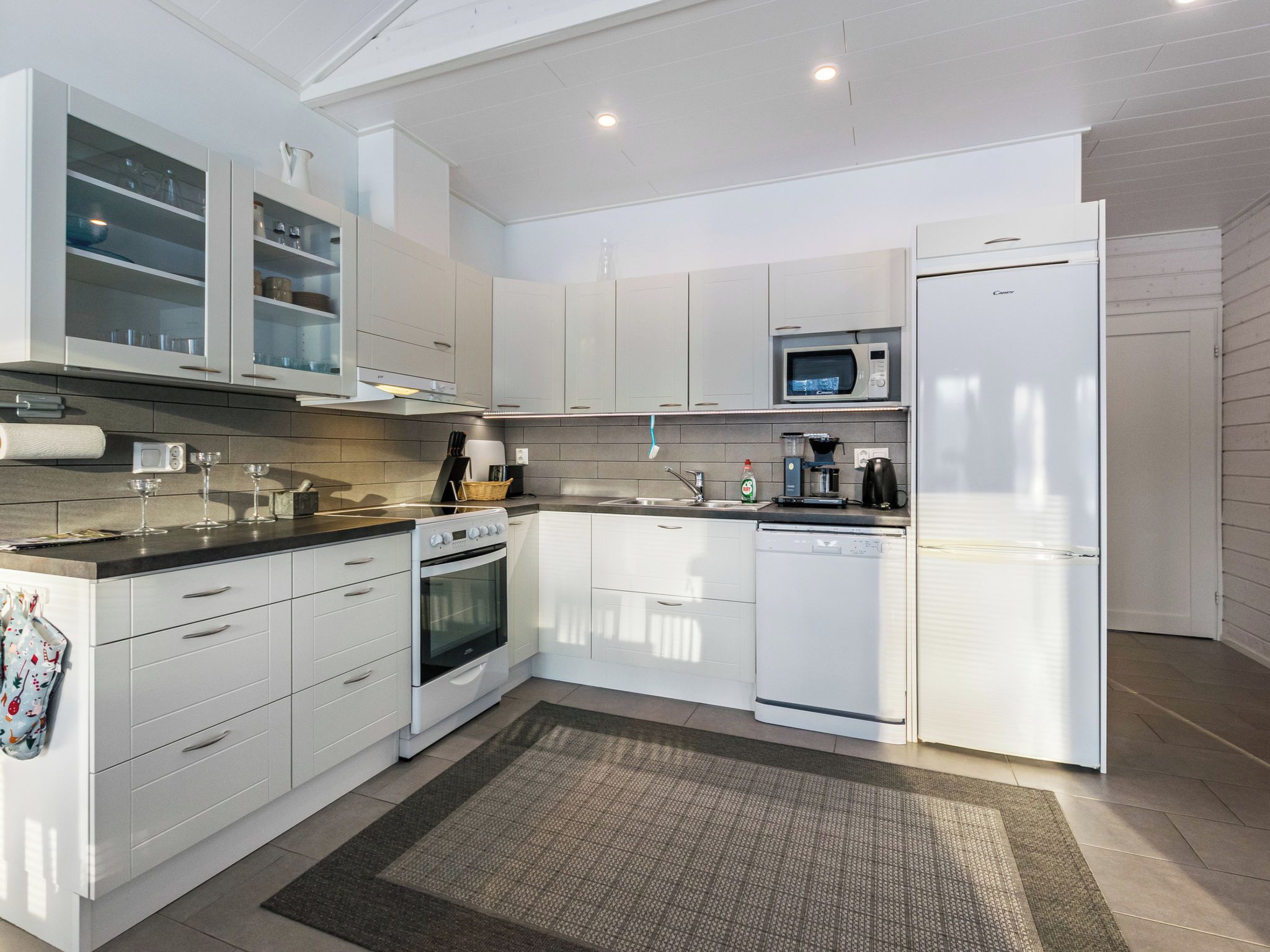 A modern kitchen with white cabinetry, a built-in oven, a microwave, and a dishwasher.