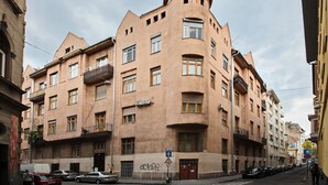 A multi-story building with a unique architectural design, featuring a rounded corner and balconies. - Unique and central apartment in a quiet side street (IX. kerület)