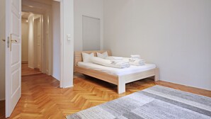 A bedroom with a wooden bed, a white headboard, and a grey striped rug. - Unique and central apartment in a quiet side street (IX. kerület)