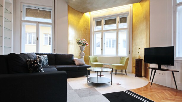 A modern living room with a black sofa, a round coffee table, and a flat-screen TV. - Unique and central apartment in a quiet side street (IX. kerület)