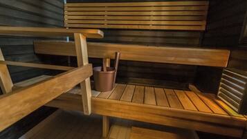 A sauna with wooden benches and a metal bucket.