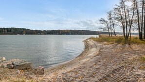 Une vue sur le lac, avec une plage de sable, des arbres et une rive éloignée.