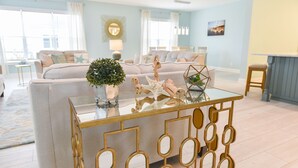 A modern living room with a glass coffee table, a sofa set, and a decorative plant.