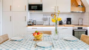 Una cocina moderna con armarios blancos, microondas y cafetera.
