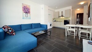 A modern living room with a blue sofa, a coffee table, and a painting of purple flowers. - Molo Lozna by Interhome (Brač/Postira)