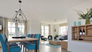 Uma sala de estar moderna com área de jantar, piso de madeira e uma janela grande.