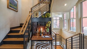 A staircase with wooden steps and black railings, leading to a landing with a table displaying bottles and a vase of flowers. - RIVER BLISS- New Hot Tub, Private, Convenient, & Perfect Location (Telluride)