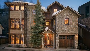 A multi-story stone house with a garage, large windows, and a snow-covered roof. - RIVER BLISS- New Hot Tub, Private, Convenient, & Perfect Location (Telluride)