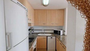 Cocina compacta con refrigerador, microondas, pileta y lavavajillas.