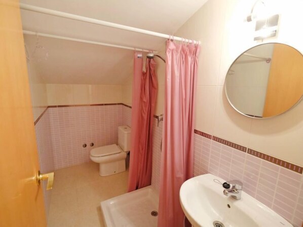 Un baño con inodoro, lavamanos y cortina de ducha.
