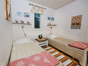 Une chambre à coucher avec deux lits, une table de chevet, une fenêtre et des éléments de décoration murale, notamment des tableaux encadrés et des figurines.
